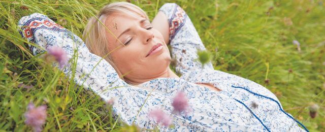 Junge Frau schläft auf der blühenden Almwiese