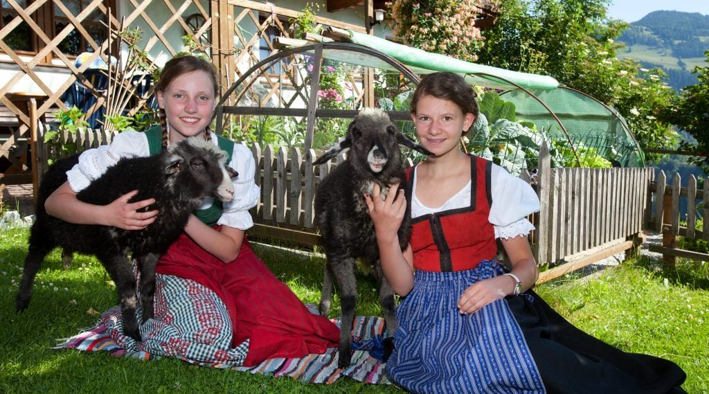 Kinder mit Schafen im Bauernhofdorf Embach.