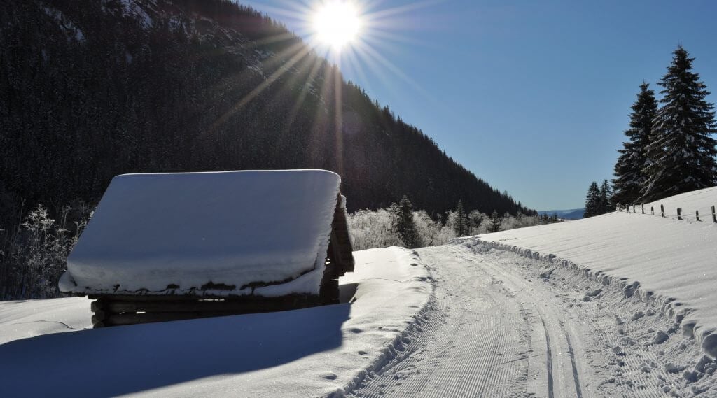 Loipe und Winterwanderweg führen an einem tief verschneiten Heustadl vorbei