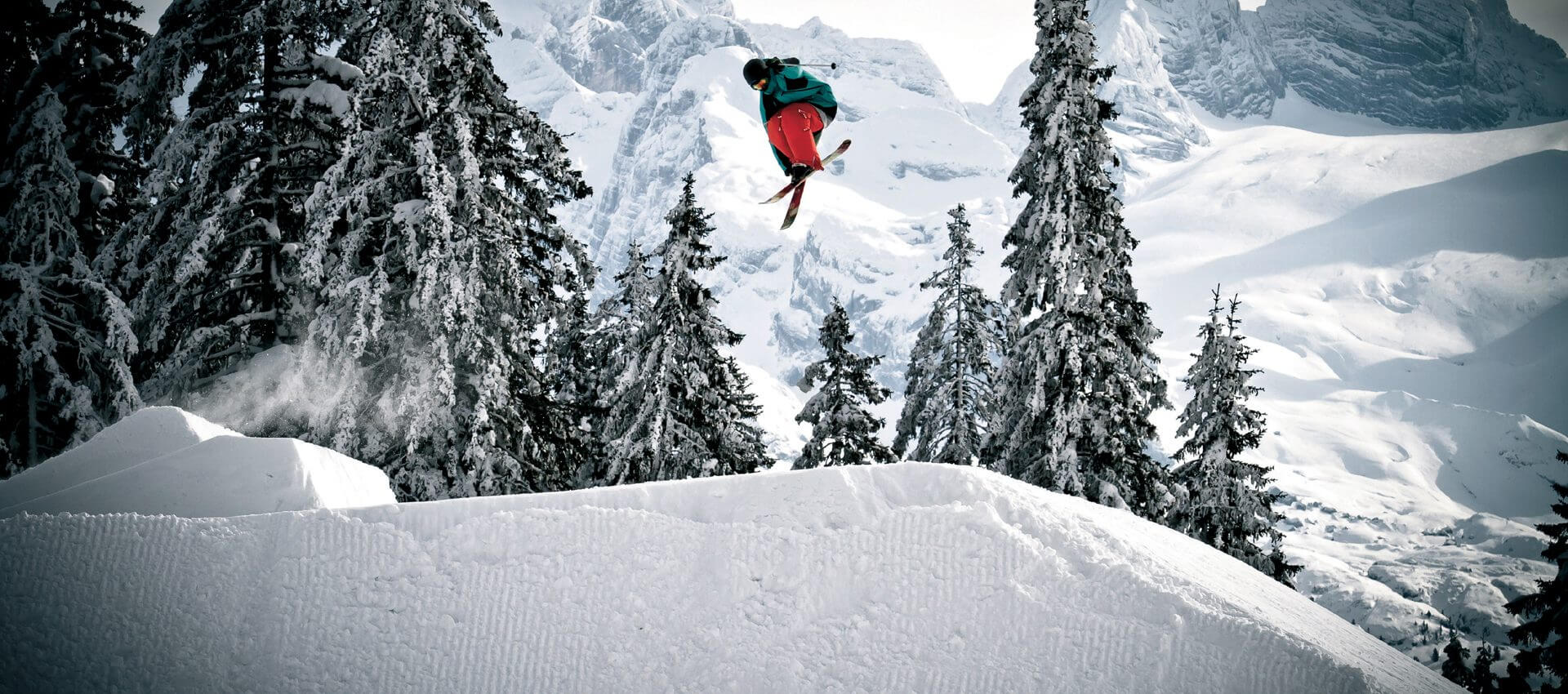 Freestyler auf Skiern hoch in der Luft in tief verschneiter Landschaft
