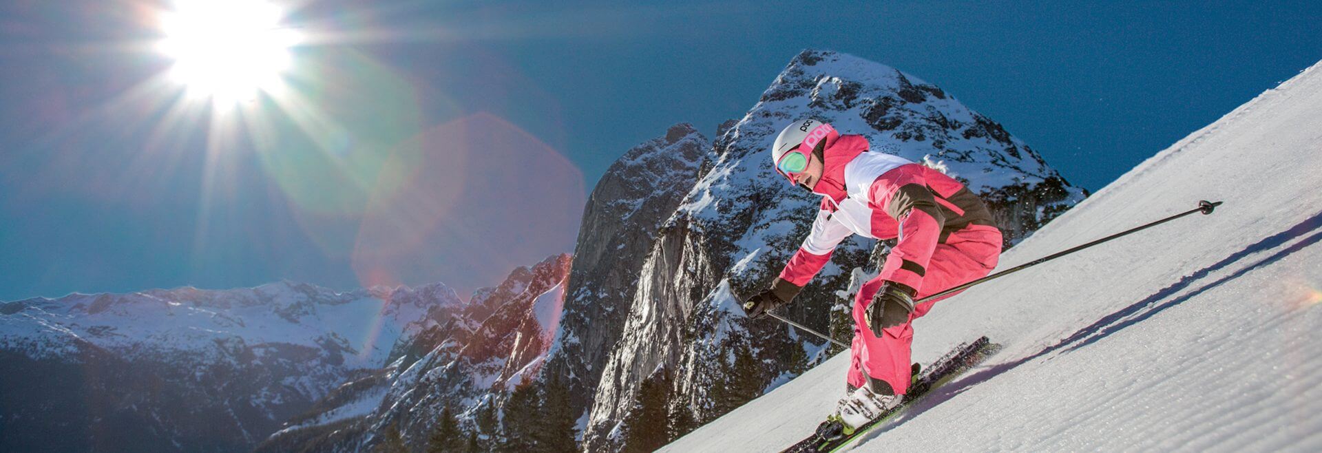 Skifahrer im rot-weißen Overall auf der frisch präparierten Piste