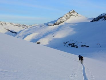Skitourengeher ziehen eine gerade Spur durch den Tiefschnee des Großvenedigers.