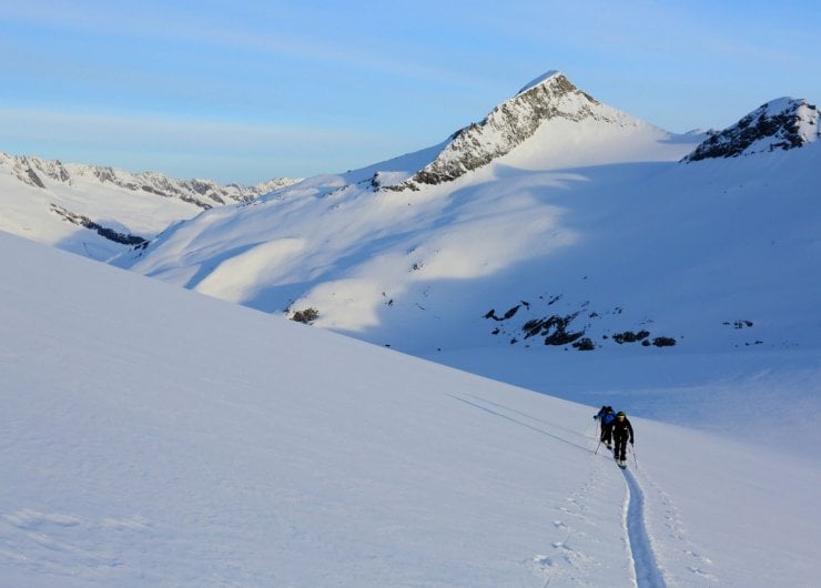 Skitourengeher ziehen eine gerade Spur durch den Tiefschnee des Großvenedigers.