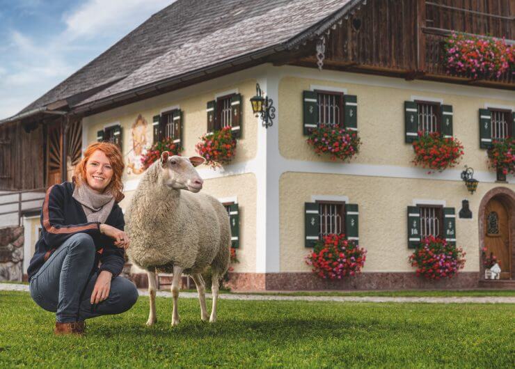 Mädchen mit Schaf vorm Bauernhof