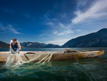 Mann mit Fischerboot und Fischernetz im See.