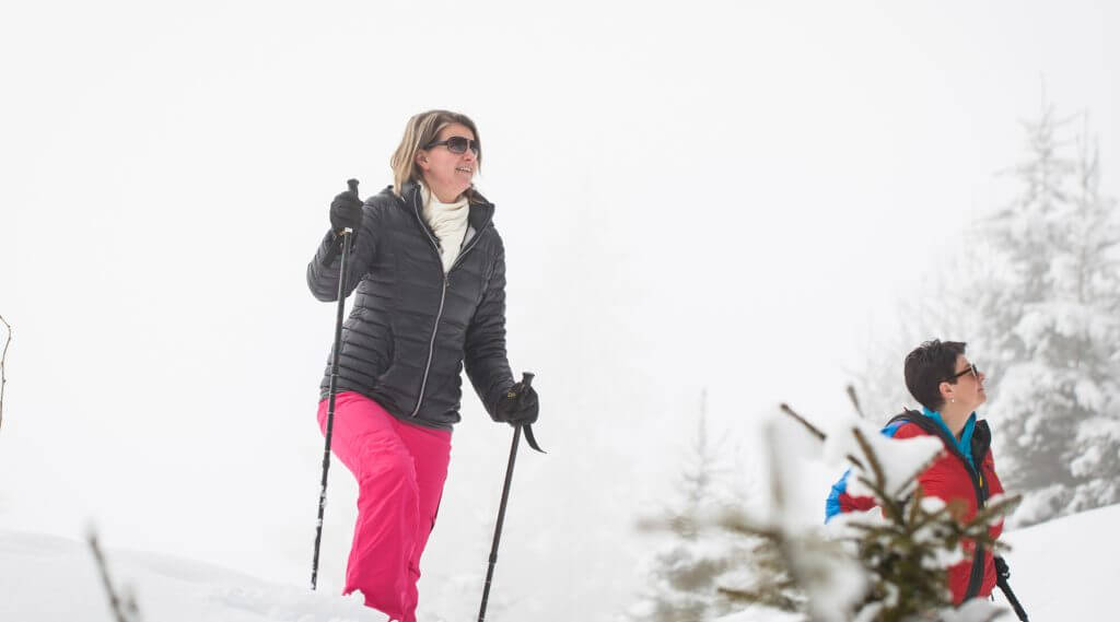 Frau in pinker Schneehose und schwarzer Jacke beim Winterwandern