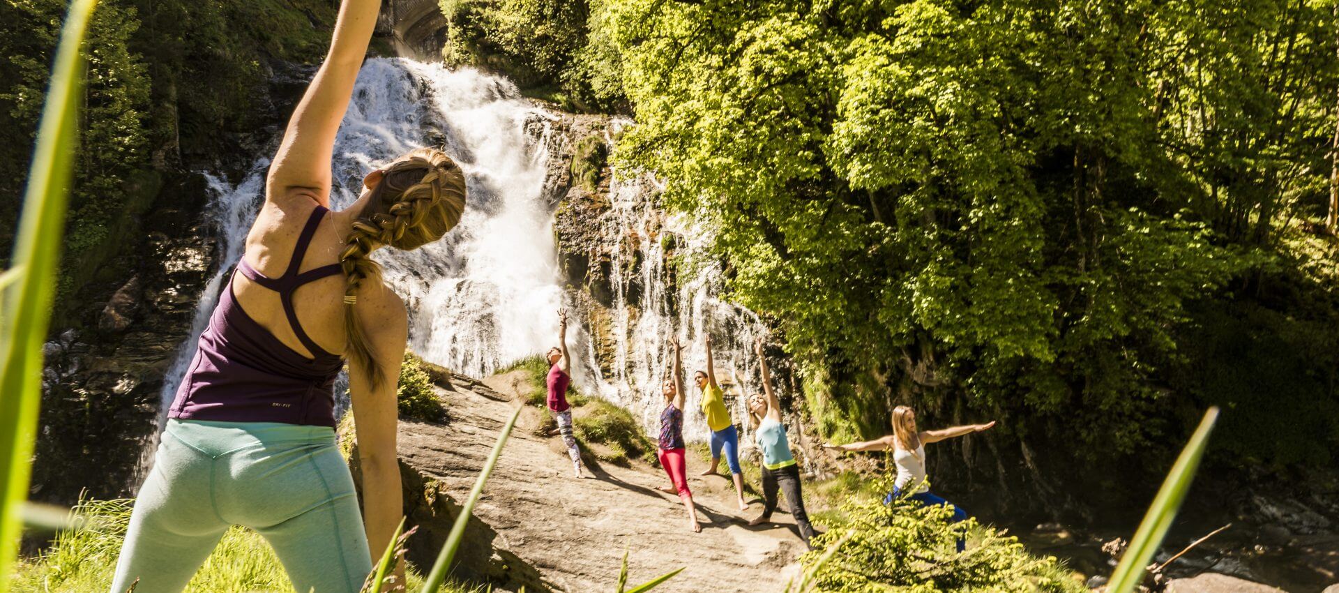 Gruppe macht Morgenyoga am Wasserfall