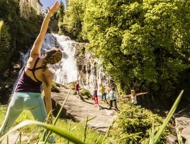 Gruppe macht Morgenyoga am Wasserfall
